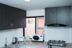 a kitchen with black cabinets and a microwave at The Serenity Space in Pātan