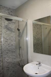 a bathroom with a sink and a shower with a mirror at Apartamentos El Yunque- Solo Familias in Conil de la Frontera