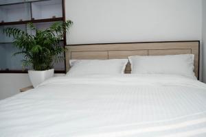 a large bed with white sheets and a plant at The Serenity Space in Pātan