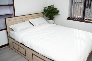 a bed with white sheets and a plant in a room at The Serenity Space in Pātan