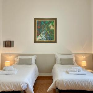 zwei Betten in einem Zimmer mit einem Gemälde an der Wand in der Unterkunft Bnbook Quadrilocale Italia in Rho