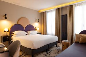 a hotel room with a large bed and a couch at Hôtel Mondial in Paris +57 photos