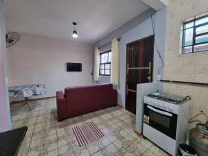 una cucina con piano cottura e divano rosso di Ohana Casa 2 Boraceia a Bertioga