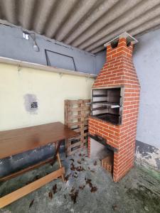 un forno di mattoni in una stanza con un tavolo di legno di Ohana Casa 2 Boraceia a Bertioga