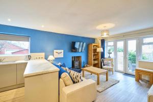 a kitchen and living room with a blue wall at Host & Stay - Kittling Nook in Bamburgh