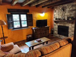 a living room with a couch and a fireplace at Cabaña La Cambera in Vega de Pas