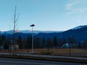 una pista de tenis con un poste de luz y montañas en Apartamenty Dworcowa 5, en Szklarska Poręba