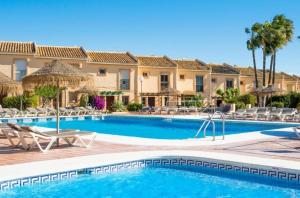 a pool at a resort with chairs and palm trees at Chalet with Sea Views in Fuengirola