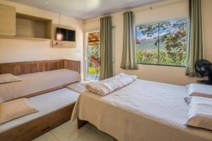 two beds in a room with a window at Pousada Bela Vista do Capão in Palmeiras