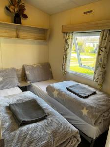 two beds in a small room with a window at Caravan Holiday Home in Great Billing