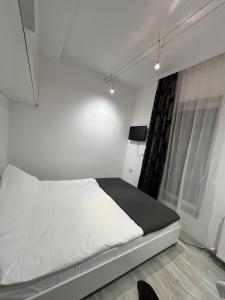 a white bedroom with a bed and a window at Luxus Cluj Airport Apartments in Cluj-Napoca