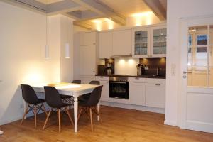 eine Küche mit weißen Schränken und einem Tisch und Stühlen in der Unterkunft Haus Boldix Whg 5 Martinique in Boldixum