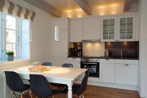 eine Küche mit weißen Schränken und einem Tisch und Stühlen in der Unterkunft Haus Boldix Whg 6 St Barth in Boldixum