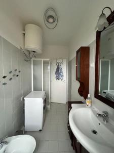 a white bathroom with a sink and a refrigerator at Delizioso appartamento sul mare in Campo Iemini