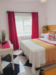 a bedroom with a bed and a window with red curtains at Orange Leaf Unit 1 in Durban +8 photos