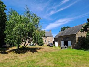an old stone building with a tree in the yard at Environnement calme et reposant - Côtes-d'Armor in Ploëzal