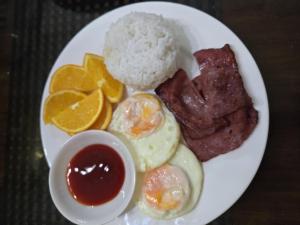 a plate of breakfast food with eggs meat and oranges at Jex Poolpoint Villa in El Nido