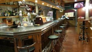 un bar avec une rangée de tabourets dans un restaurant dans l'établissement Pensión Avenida, à Vilafranca del Penedès