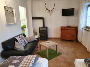 ein Wohnzimmer mit einem schwarzen Ledersofa und einem Holzofen in der Unterkunft Landhaus Steirerengel in Lócs