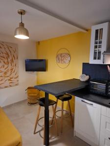 a kitchen with a table and stools in a room at Le gîte des Pierres Dorées in Marcilly-dʼAzergues