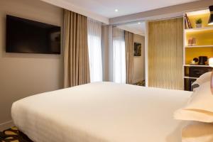 a bedroom with a large white bed and a television at Hôtel Mondial in Paris