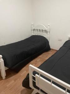 パラナにあるDepto Jose Hernandez tres dormitoriosの黒いシーツが備わる客室内のベッド2台