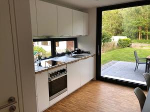 Una cocina con gabinetes blancos y una ventana grande. en -"Strandhaus Friedrich"-, en Dierhagen
