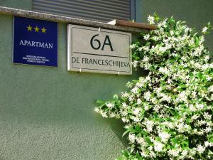 ein Schild an der Seite eines Gebäudes mit Blumen in der Unterkunft Apartments Karmen Pula in Pula