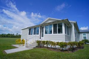 a white house with a porch and chairs in a field at Lakeside Cottages in Lake Placid