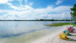 een rij kleurrijke stoelen op een strand bij het water bij Lakeside Cottages in Lake Placid