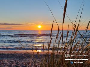 a sunset over the ocean with a sandy beach at 365PAM - Apartament Dobra Aura w Summer Lofts in Ustronie Morskie +20 photos
