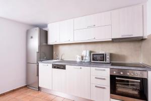 a kitchen with white cabinets and a microwave at Villa Erofili in Fira +52 photos