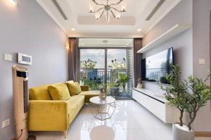 een woonkamer met een gele bank en een groot raam bij Cozy Nest Vinhomes in Ho Chi Minh-stad