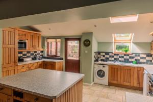 eine Küche mit Holzschränken, einer Waschmaschine und einem Trockner in der Unterkunft Wetheral at Wetheral Cottages in Great Salkeld + 16 Fotos