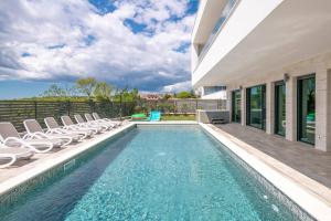 a swimming pool with chairs and a house at Villa ReMi mit 2 Whirlpools und Meerblick in Premantura