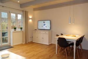 ein Wohnzimmer mit einem Tisch und einem TV an der Wand in der Unterkunft Haus Boldix Whg 4 Cayman in Boldixum