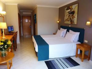 a hotel room with a large bed and a desk at Hotel Belavista Da Luz in Luz