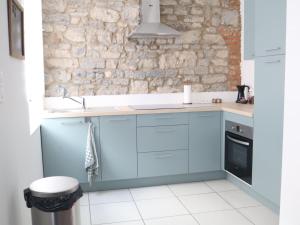 a kitchen with blue cabinets and a stone wall at Escapade Givetoise in Givet +7 photos