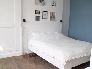 a white bed in a room with white walls at Escapade Givetoise in Givet