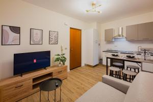 a living room with a tv and a kitchen at Bilocale Chic vicino al Teatro in Udine +7 photos