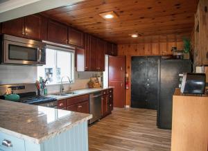 eine Küche mit Holzschränken und einem Edelstahlkühlschrank in der Unterkunft Views of Ocean and Iconic Morro Rock, Beach Cottage in Morro Bay + 10 Fotos