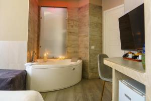 a bathroom with a tub with a television and a bed at Corso Boutique Luxury Rooms in Rome