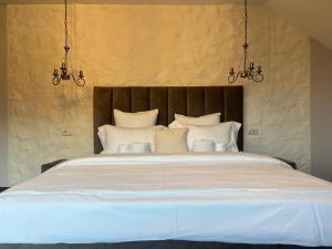 a bedroom with a large white bed with two chandeliers at Crai Stone House in Bran