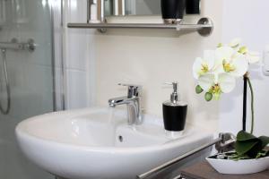 a white sink in a bathroom with flowers on it at Ferienzimmer 1 Engelmann-Beck in Hanstedt +8 photos