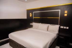 una camera da letto con un letto grande con lenzuola bianche di City Base Hotel, Port Harcourt a Port Harcourt Altre 37 foto