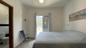 a bedroom with a bed and a chair next to a door at Casa aconchegante perto da Praia de Massaguacu in Massaguassu