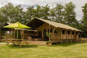 StoutenburgZorgcamping De Ruif De Peppelhoeve的一座带帐篷、桌子和雨伞的房子