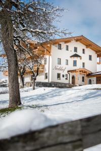 a white building with a tree in the snow at Nockhof in Terfens