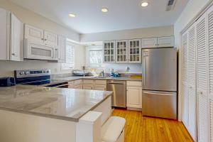 a kitchen with white cabinets and a stainless steel refrigerator at Parkside 4518 in Kiawah Island