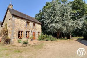 an old stone house with a tree in the background at La loge du bourg in Lanrigan
